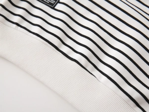 Detail of black and white striped sweatshirt with elastic ribbed hem and woven label