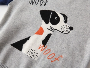 Close-up of knit fabric texture and dog pattern with WOOF text on kids sweater