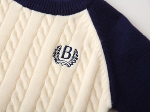 Detailed cable knit pattern on boys' sweater featuring contrast collar and embroidered B logo