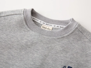 Détail de l'encolure d'un sweat-shirt gris avec col côtelé et bande de propreté logotée