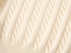 Close-up of cream cable-knit texture and ribbed cuffs on a boys' warm sweater