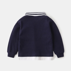 Detail view of navy waffle knit texture and mock two-piece hem on boy's polo shirt