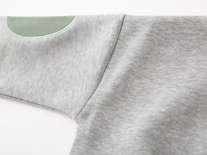 Detail view of heather gray sweatshirt fabric with green elbow patch and fine stitching