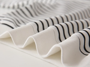 Close-up of black and white striped knit sweater showing ribbed cuffs and premium texture