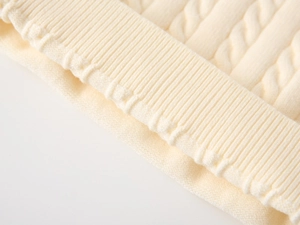 Detail of cream cable knit texture and ribbed cuff on boys' cotton blend sweater