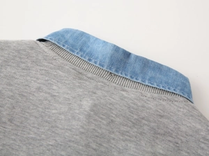 Detail of grey knitted sweater featuring a blue denim collar and fine ribbed stitching
