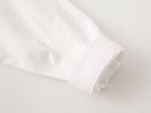 Detailed macro view showing the fine stitching and folded cuff of this white cotton shirt