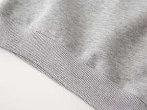 Detailed macro view of the grey mélange fabric and ribbed hem of the boy's sweatshirt