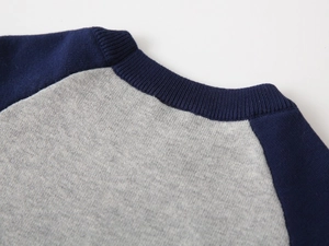 Detail of navy blue and grey raglan sleeve seams on kids knitted sweater