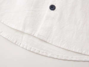 Detail of white cotton linen boy shirt featuring curved hem and high-quality texture