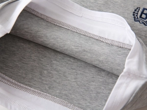 Détail du tricot gris avec bordure blanche contrastée et broderie B de haute qualité