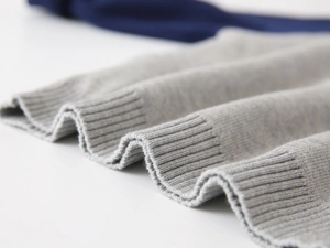 Macro shot of grey knit sweater showing detailed ribbed cuffs and high-quality texture