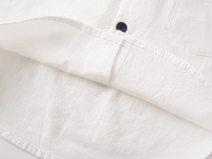 Macro view of white cotton shirt curved hem and contrast navy button sewing detail