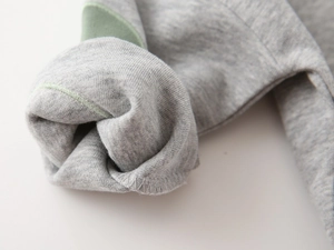 Close-up of grey cotton blend fabric showing soft brushed fleece lining and neat overlock stitching