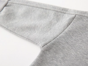 Détail du tissu en maille gris chiné et des coutures de qualité du pull pour enfant