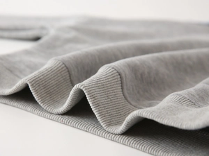 Close-up of ribbed cuffs and hem on a gray knitted sweatshirt for kids with soft texture