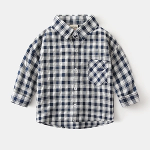 Détail macro du motif à carreaux bleu marine et blanc sur chemise enfant