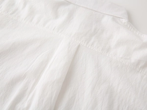 Detailed macro view of the back yoke and box pleat on a white cotton boy's shirt