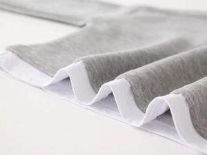 Détail de l'ourlet à double couche sur l'ensemble de sport gris et blanc pour enfant