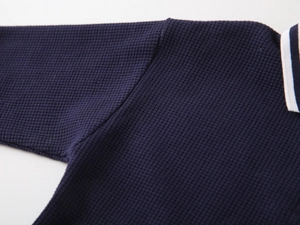 Detail of navy waffle knit polo shirt showing textured fabric and striped collar trim