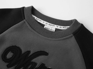 Détail d'un sweat en polaire pour enfant avec col côtelé et broderie fine