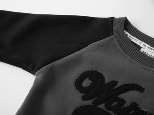 Détail du sweat-shirt enfant avec col ras du cou côtelé et broderie de lettres design