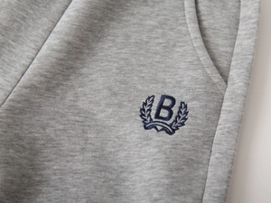 Détail du pantalon de jogging gris montrant le coton doux et le logo B brodé avec soin