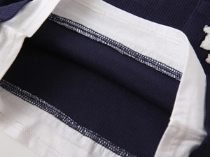 Detail view of navy blue waffle knit fabric and layered hem design on kids polo shirt