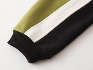 Macro detail of the three-color patchwork knit sleeves and ribbed black cuffs of the jacket