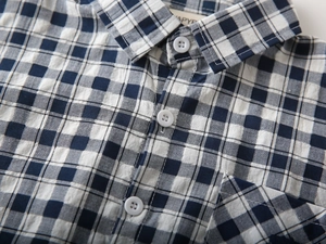 Détail du col de la chemise à carreaux bleu et blanc avec bouton blanc et texture en coton