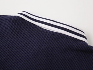 Detail of dark blue waffle knit texture and white striped polo collar on children's shirt