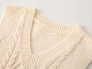 Detail of V-neck knitted sweater vest with cable knit pattern and soft cream texture