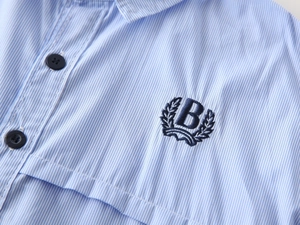 Macro shot of blue striped boy shirt featuring navy laurel wreath B embroidery