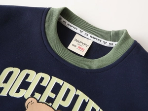 Detail of blue boy sweatshirt featuring green ribbed neckline and cartoon bear print