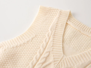 Detail of V-neck knitted vest showing textured cable and honeycomb stitch patterns