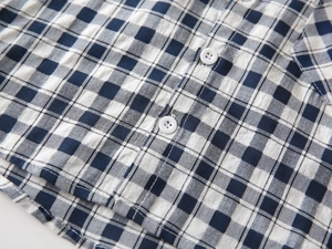 Détail de la texture gaufrée seersucker à carreaux bleu et blanc d'une chemise enfant