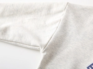 Detail view of the stitching and soft knit fabric of a light grey boys' sweatshirt
