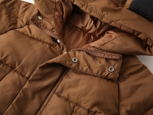 Detail view of winter jacket featuring durable metal snap buttons and resin zipper closure