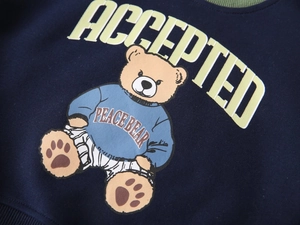 Detail of navy blue kids sweatshirt featuring a cartoon peace bear and letter print