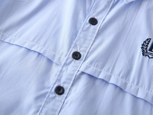 Close-up of boys light blue striped cotton shirt with laurel leaf embroidery detail