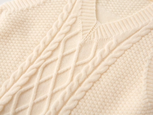 Detail of V-neck cream cable knit sweater vest with delicate textured patterns