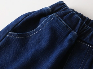 Detailed close-up of elastic waistband and stitching on boys indigo blue denim pants