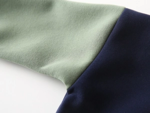 Detail shot of sage green and navy blue cotton fabric with flat seam stitching