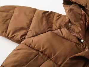 Close-up of brown hooded winter coat with quilted texture, zip and metal snaps