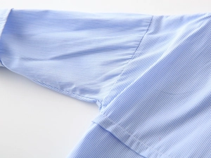 Detail shot of blue and white striped fabric stitching on a boys long sleeve shirt