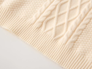 Close-up of beige knit vest showing cable-knit texture and soft ribbed details