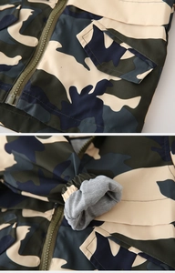 Detail view of camouflage kids jacket showing resin zipper, pocket and elastic cuffs