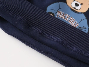 Detail of ribbed cuff on dark blue sweatshirt featuring a cute cartoon peace bear print