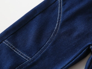 Detail of dark blue denim fabric with visible twill texture and double white stitching