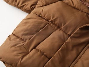 Close-up of caramel brown quilted winter jacket with smooth windproof fabric and pocket